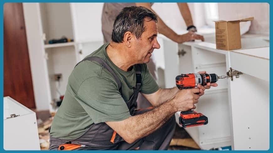 Man with power tool installing cabinets